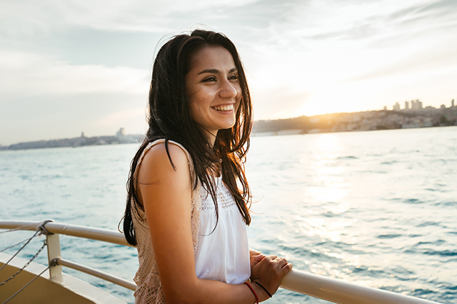 woman smiling aboard river cruise ship as the sun sets