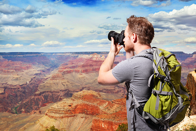 travel photography tips - man taking a photo overlooking mountains
