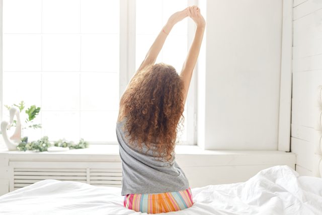 girl stretching in bed - melatonin for jet lag?