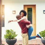 Shot of a young couple celebrating the move into their new house - how much to put down on a house.