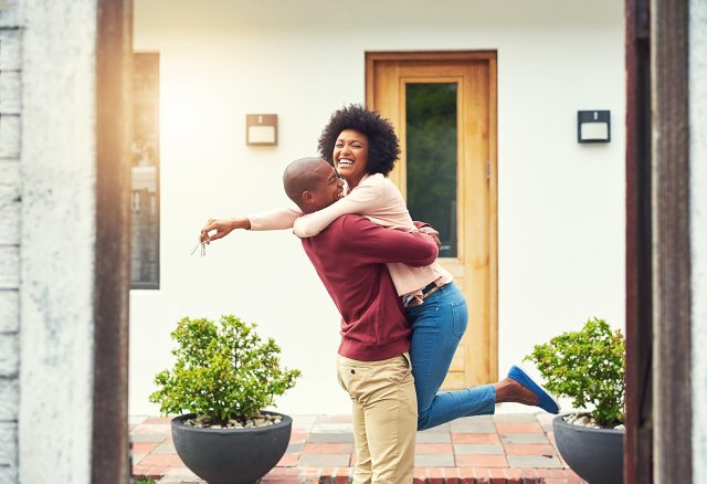 Shot of a young couple celebrating the move into their new house - how much to put down on a house.