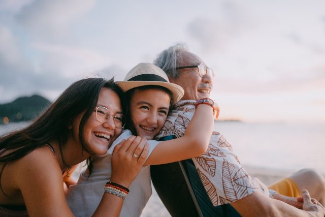 Happy grandfather and granddaughters having a good time on beach at sunset, Okinawa, Japan