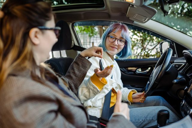 Teenager girl having driving lesson with female instructor