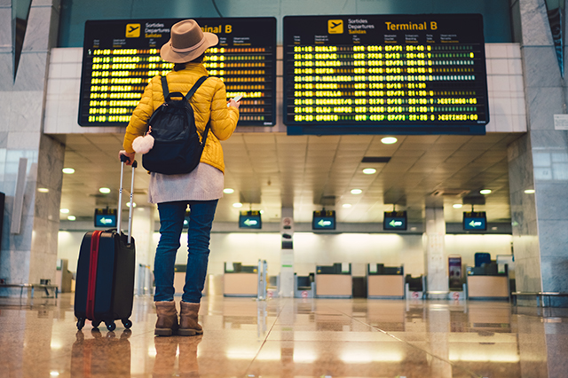 Women looks at airport arrival-departure board.