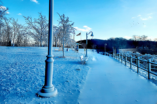 A light layer of snow on a walkway by the water.