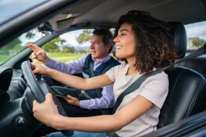 Driving instructor teaching a young woman how to drive - learning to drive concepts