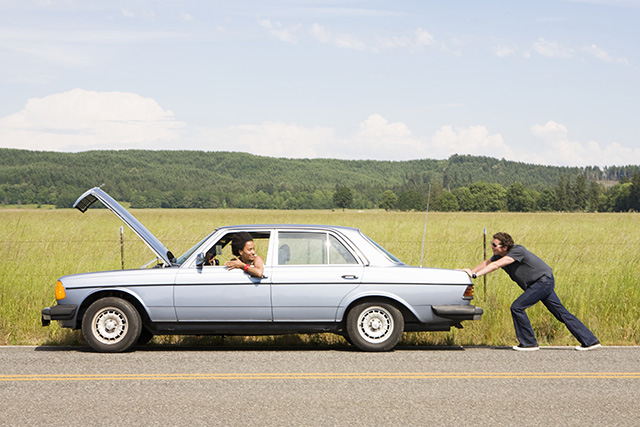 Man pushing broken down car